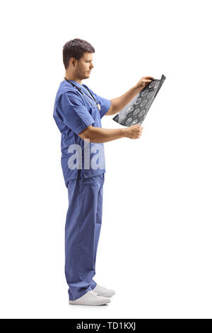 Full length profile shot of a young male doctor in a blue uniform looking at x-ray image isolated on white background Stock Photo