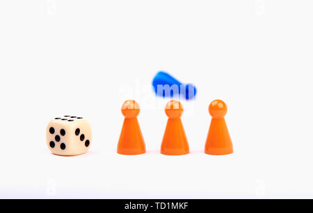 Three orange game pieces with a dice and a blue figure lying behind them. Isolated on white background. Stock Photo