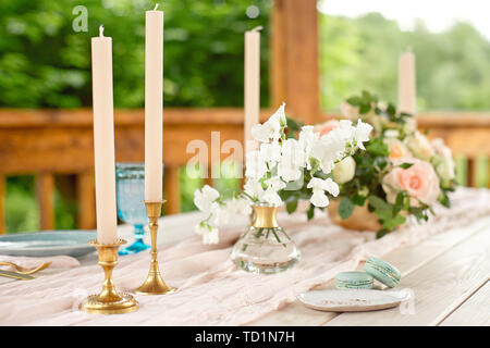 Decorated table for dinner for two person, with plates knife, fork, cheese, wine, wine glasses and flowers in a copper vase. Stock Photo