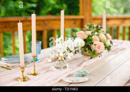 Decorated table for dinner for two person, with plates knife, fork, cheese, wine, wine glasses and flowers in a copper vase. Stock Photo