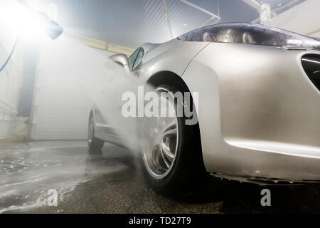 Cleaning Car Using High Pressure Water. Man washing his car under high pressure water in service. man worker washes car. self-service Stock Photo