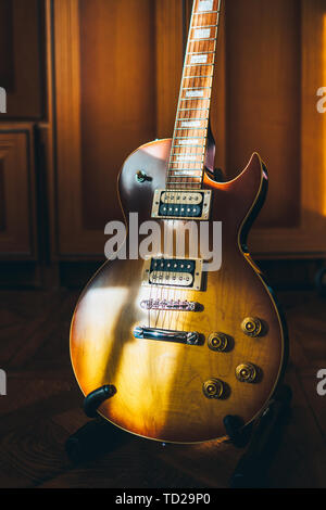 Brown sunburst electric guitar in sunlight on wooden floor. Cozy image of musical instrument at home. Stock Photo