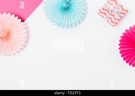 Party flat lay background of gift box and tissue paper decorations of pink and blue colors on white table with free space in center. Stock Photo