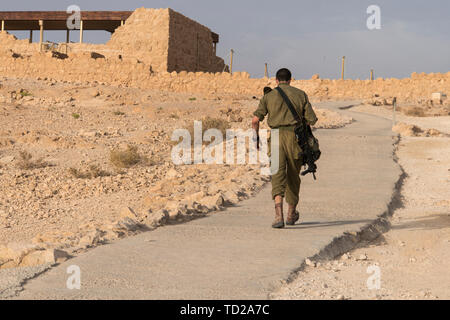 Back view of military going alone among deserted territory somewhere in the middle east. Masada fortification, Israel, war trainning. Tired soldier Stock Photo