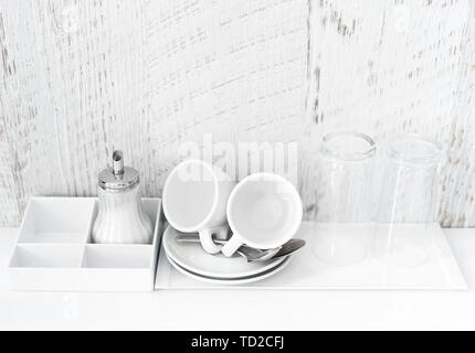Coffee and tea making set of white cups, saucers, tea spoons and glasses on white porcelain tray. Hotel accomodation. Copy space. Stock Photo