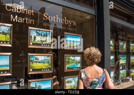 A woman looking at property details on estate agent's window, Dinard, Brittany, France Stock Photo