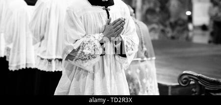 priest with hands joined in prayer in church with his brothers Stock Photo