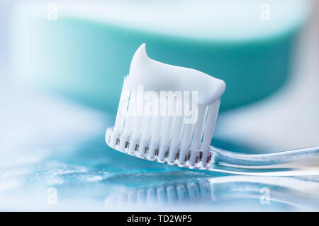 Plastic toothbrush with white toothpaste on a blue table Stock Photo