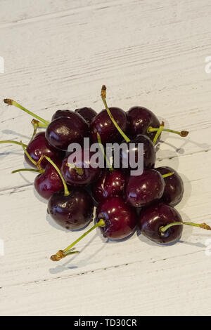 A bunch of newly picked cherries on a white planked painted board Stock Photo