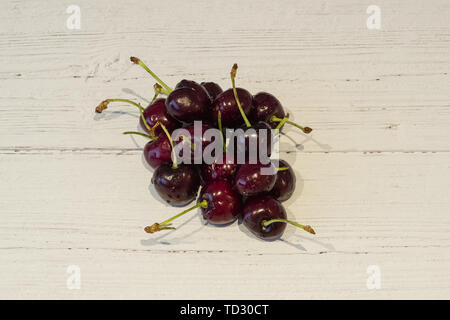 A bunch of newly picked cherries on a white planked painted board Stock Photo