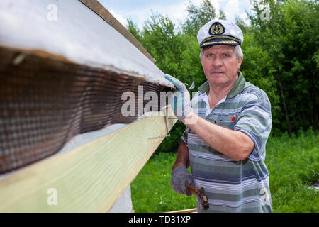 Carpenter framing gable end, with many roof trusses in background Stock