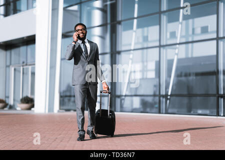 Calling Taxi. Businessman Arriving At Airport, Walking Outdoors Stock Photo