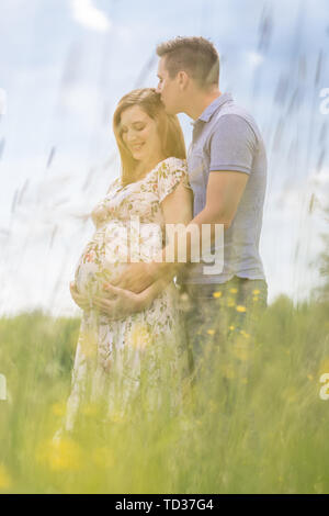 Portrait of man hugging his pregnant wife while standing Stock Photo ...