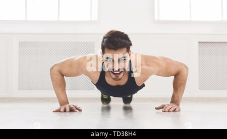 Young muscular man pushing ups in studio Stock Photo