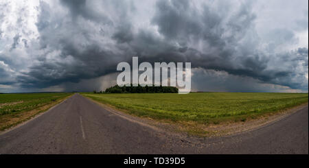 hdr panorama on asphalt road among fields in evening with awesome black clouds before storm Stock Photo