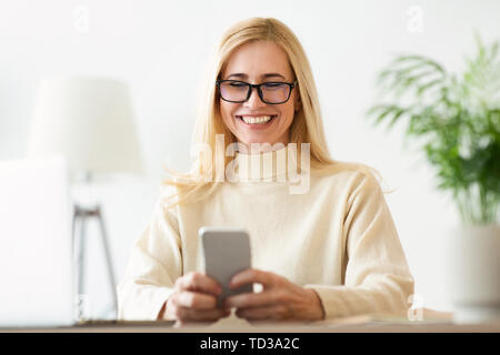 Happy Mature Woman Reading Text Message On Phone Stock Photo