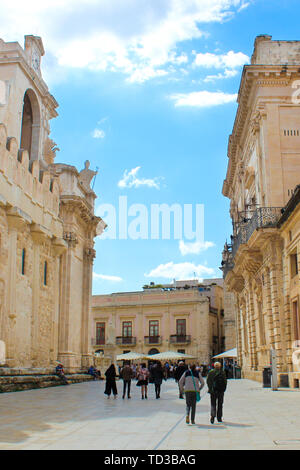 Syracuse, Italy - Apr 10th 2019: Vertical picture of tourists walking to the Piazza Duomo Square along beautiful Roman Catholic Cathedral of Syracuse in Ortigia Island, Sicily, Italy. Tourist spot. Stock Photo