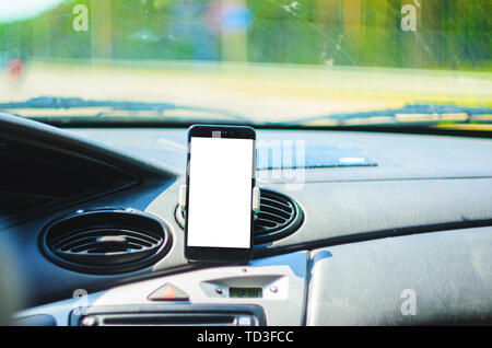 Smartphone on the front of the car as a navigator. Cut out the white background of the screen of the smartphone for placing graphics Stock Photo