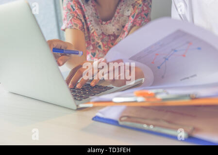 Close up photo of woman holding document and using laptop Stock Photo