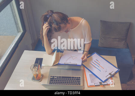 Young lady focusing on analyzing sales chart document with laptop Stock Photo