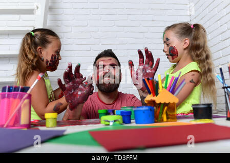 Creativity and imagination. Fathers day and family concept. Body art and painting. Girls drawing on man face skin with colorful paints. Daughters and  Stock Photo