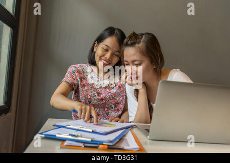 Two young happy women working with laptop and business document Stock Photo