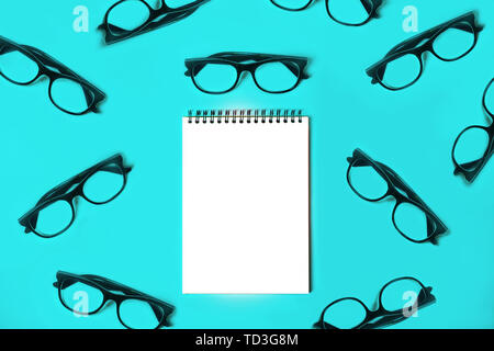 Notepad with trendy glasses on blue background. Stock Photo