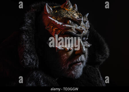 Severe king of perpetual cold kingdom wearing black fur coat. Magical creature with horns on head and golden dragon skin, supernatural concept. Demon Stock Photo