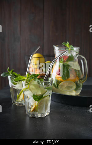Detox lemonade with lime, orange, lemon, strawberry in glass and jar. Summer healthy freshness drink. Dark wooden background. Stock Photo