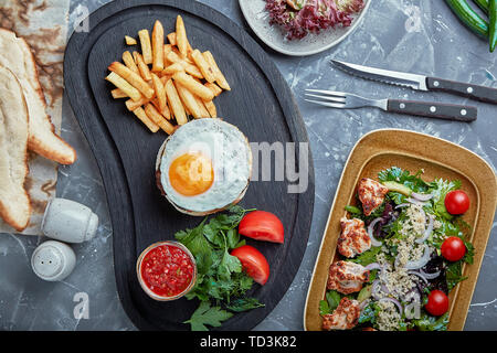 Beef steak with egg and salad from greens and vegetables. Wooden background, table setting, fine dining Stock Photo