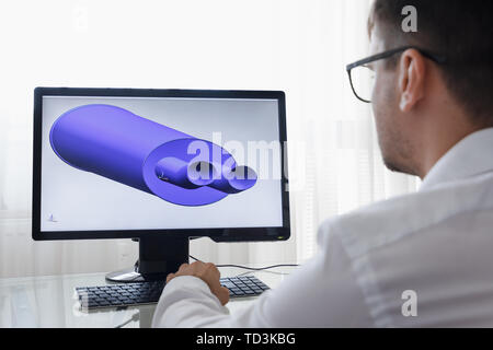 Engineer, Constructor, Designer, Architekt in Glasses Working on a Personal Computer. He Creating New Component of Car Muffler in CAD Program. Freelan Stock Photo