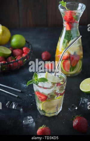 Detox lemonade with lime, orange, lemon, strawberry in glass and jug. Stock Photo