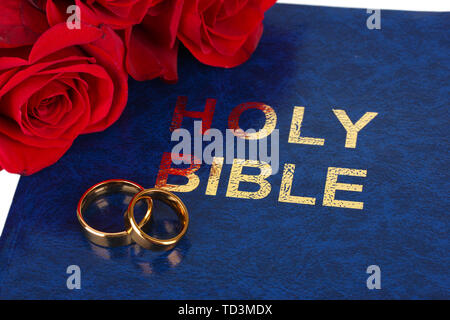 Wedding rings with roses on bible Stock Photo