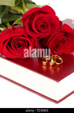 Wedding rings with roses on bible isolated on white Stock Photo