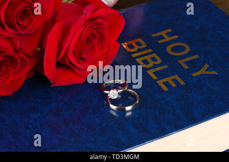 Wedding rings with roses on bible Stock Photo