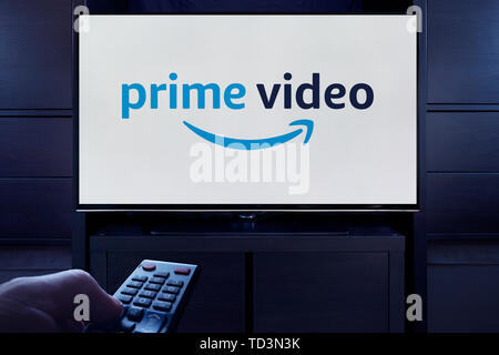 A man points a TV remote at the television which displays the logo for the Prime Video on demand video streaming service (Editorial use only). Stock Photo