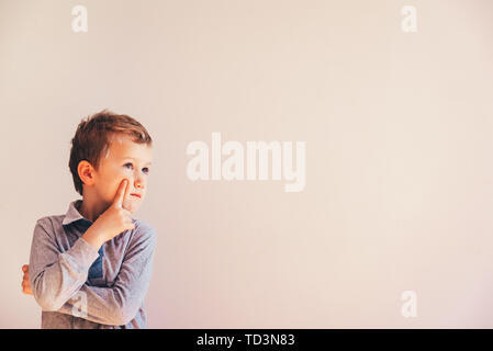 Thoughtful boy with doubts about his ideas, on white background with area copy space. Stock Photo