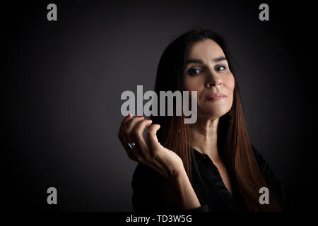 Portrait of middle-aged woman with interaction with hands. Dark background. Stock Photo