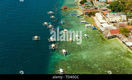 Tourists snorkeling over coral reef with clear blue ocean water, aerial view. Moalboal, Philippines. People swim in the transparent sea between coral reefs. Summer and travel vacation concept. Stock Photo