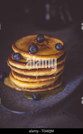 American Pancakes with Organic Berries and Maple Syrup on Dark Moody Background. Classic Homemade Breakfast. Stock Photo