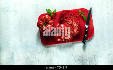 sliced Beefsteak tomato on a red cutting board and a knife. cooking healthy summer meals Stock Photo