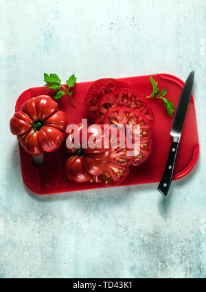 sliced Beefsteak tomato on a red cutting board and a knife. cooking healthy summer meals Stock Photo