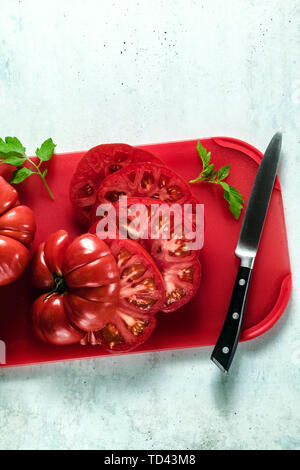 sliced Beefsteak tomato on a red cutting board and a knife. cooking healthy summer meals Stock Photo
