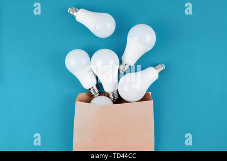 Energy-saving and eco-friendly life in conceptual frame pattern. Creative top view flat lay of LED light bulbs in craft paper shopping bag composition Stock Photo