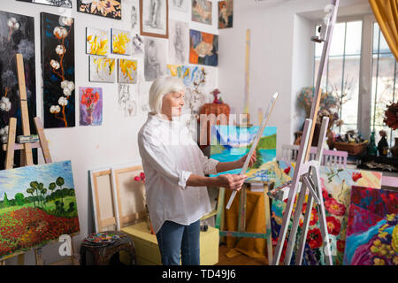 Artist feeling inspired. Talented mature beautiful artist feeling truly inspired looking at her picture Stock Photo