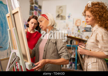 Looking at artist. Two young talented women looking at famous artist painting on canvas Stock Photo