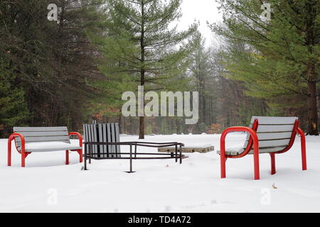 Fire pit in a park on a snowy day with no people occupying its benches Stock Photo