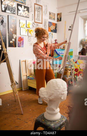 Excited and inspired. Cheerful young artist feeling excited and inspired while painting Stock Photo