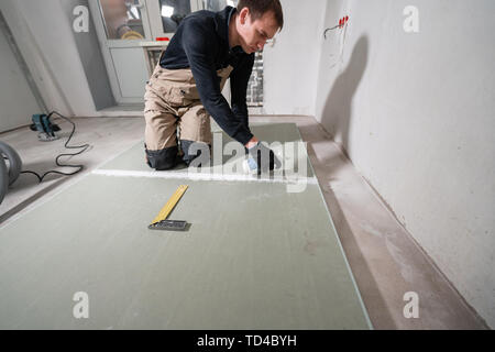 Worker is using a polyurethane foam for gluing drywall at ninety degrees. Hand holding polyurethane expanding foam glue gun applicator Stock Photo