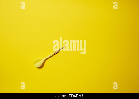Single yellow arrow dart isolated on yellow background Stock Photo